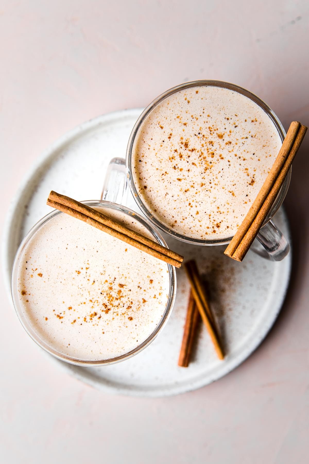 2 mugs of hot buttered rum with cinnamon sticks