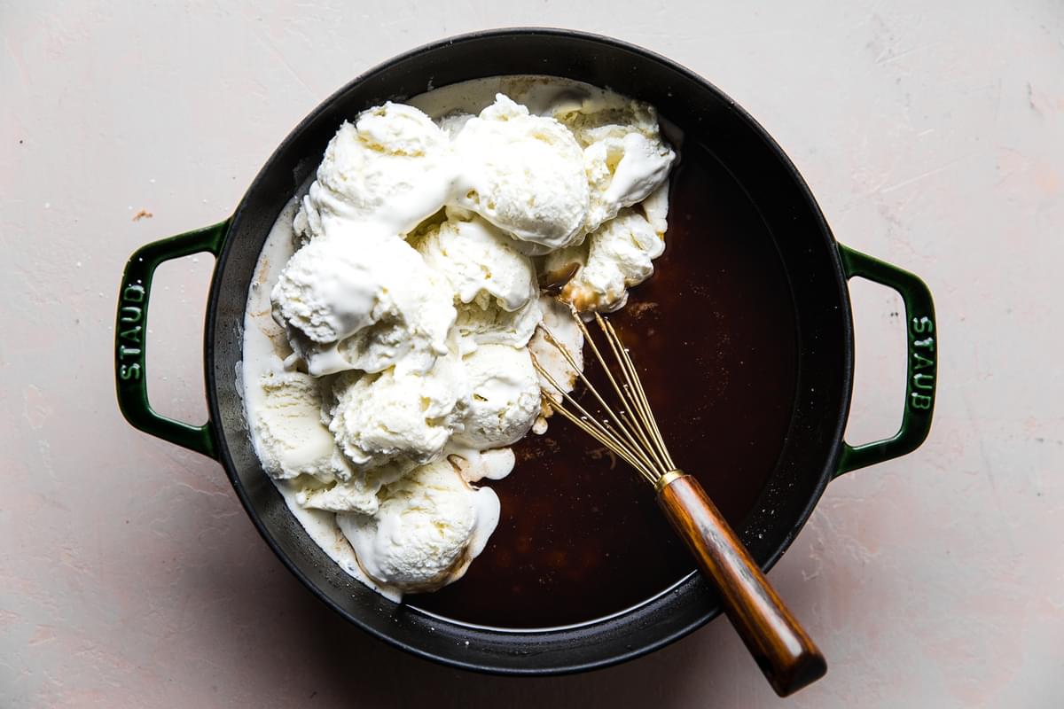 ice cream bring added to hot buttered rum batter in a pot with a whisk