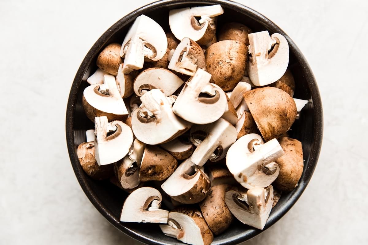 quartered brown crimini mushrooms in a bowl
