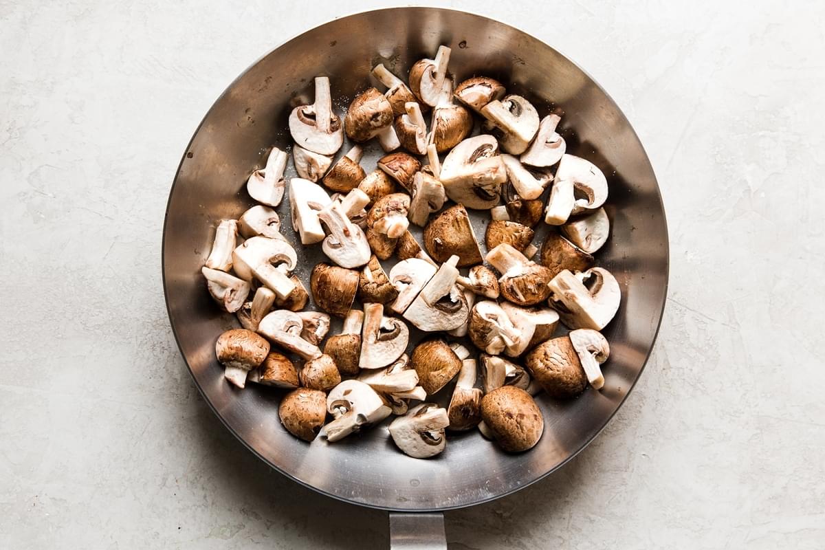 quartered brown crimini mushrooms in a sauté pan
