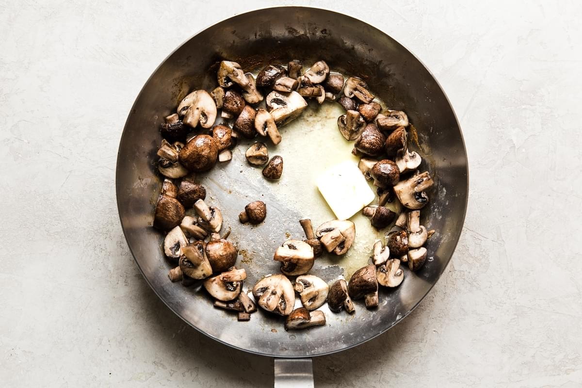 brown crimini mushrooms in a pan with butter