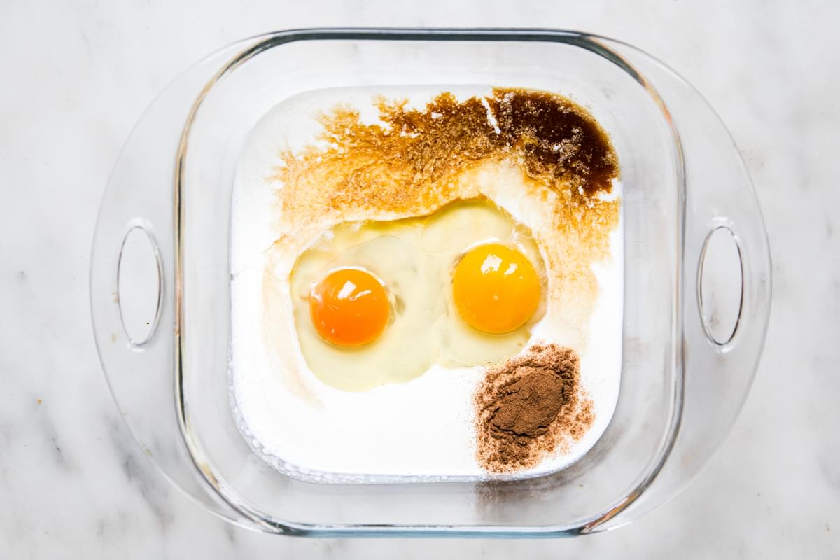two eggs, heavy cream, vanilla extract and cinnamon in a glass 8x8 baking dish on the counter