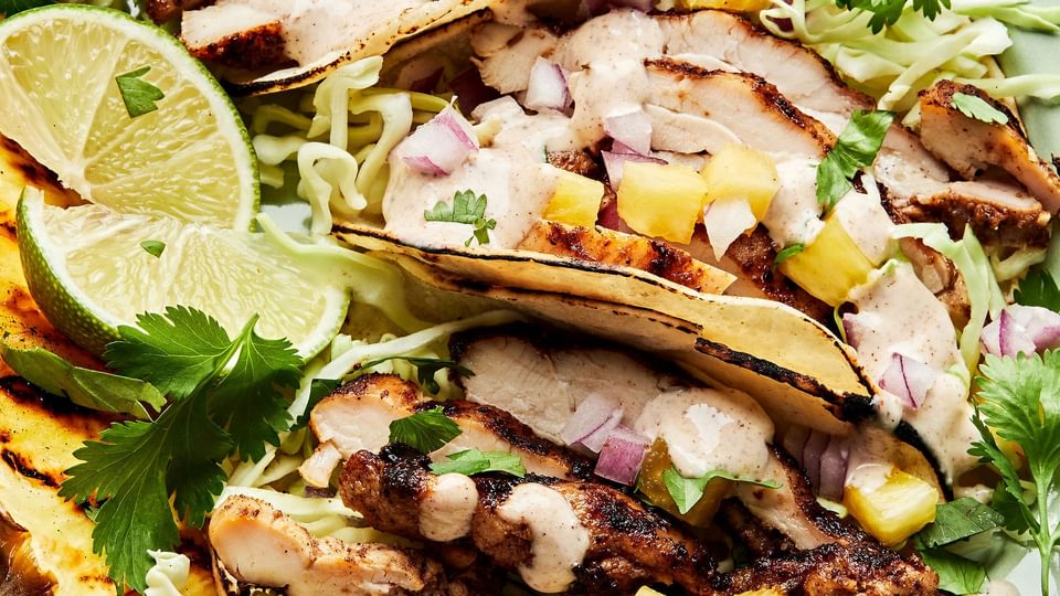 jerk chicken tacos topped with onion, pineapple, cabbage, cilantro and jerk aioli. served with a wedge of grilled pineapple