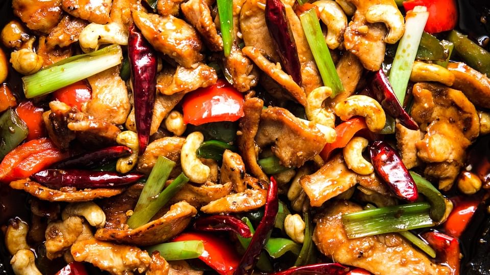 kung pao chicken in a cast iron skillet with cashews and bell peppers