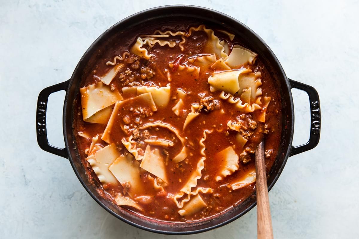 lasagna soup in a soup pot with a wooden spoon.