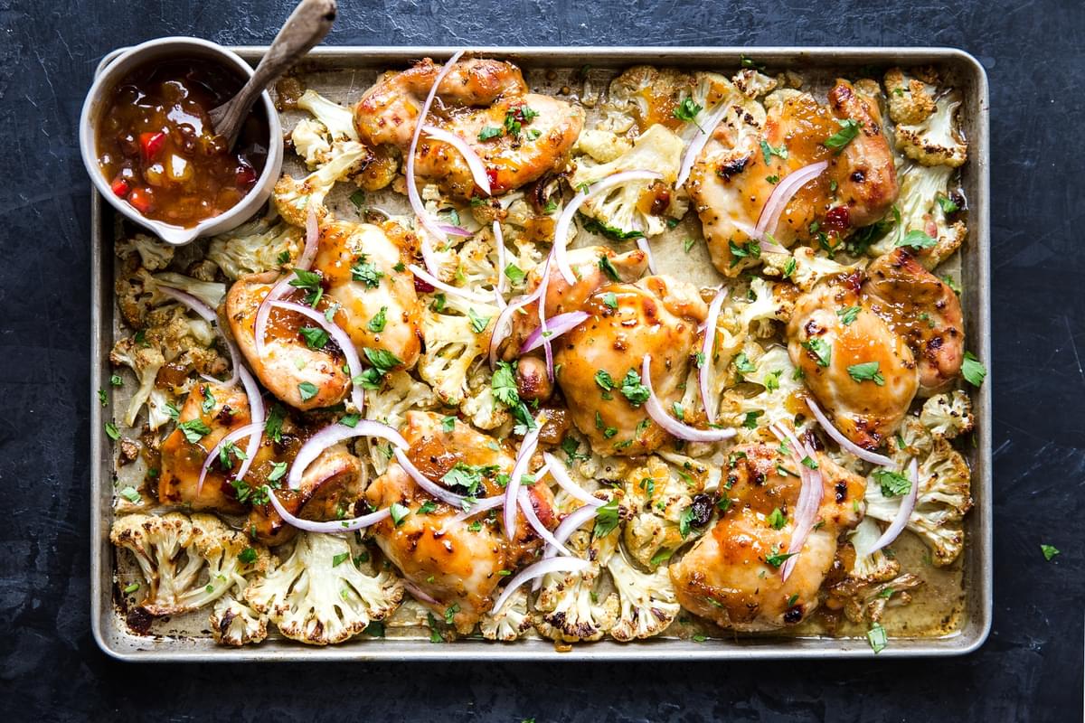Mango Chutney Sheet Pan Chicken With Cauliflower on a baking sheet with red onion and cilantro