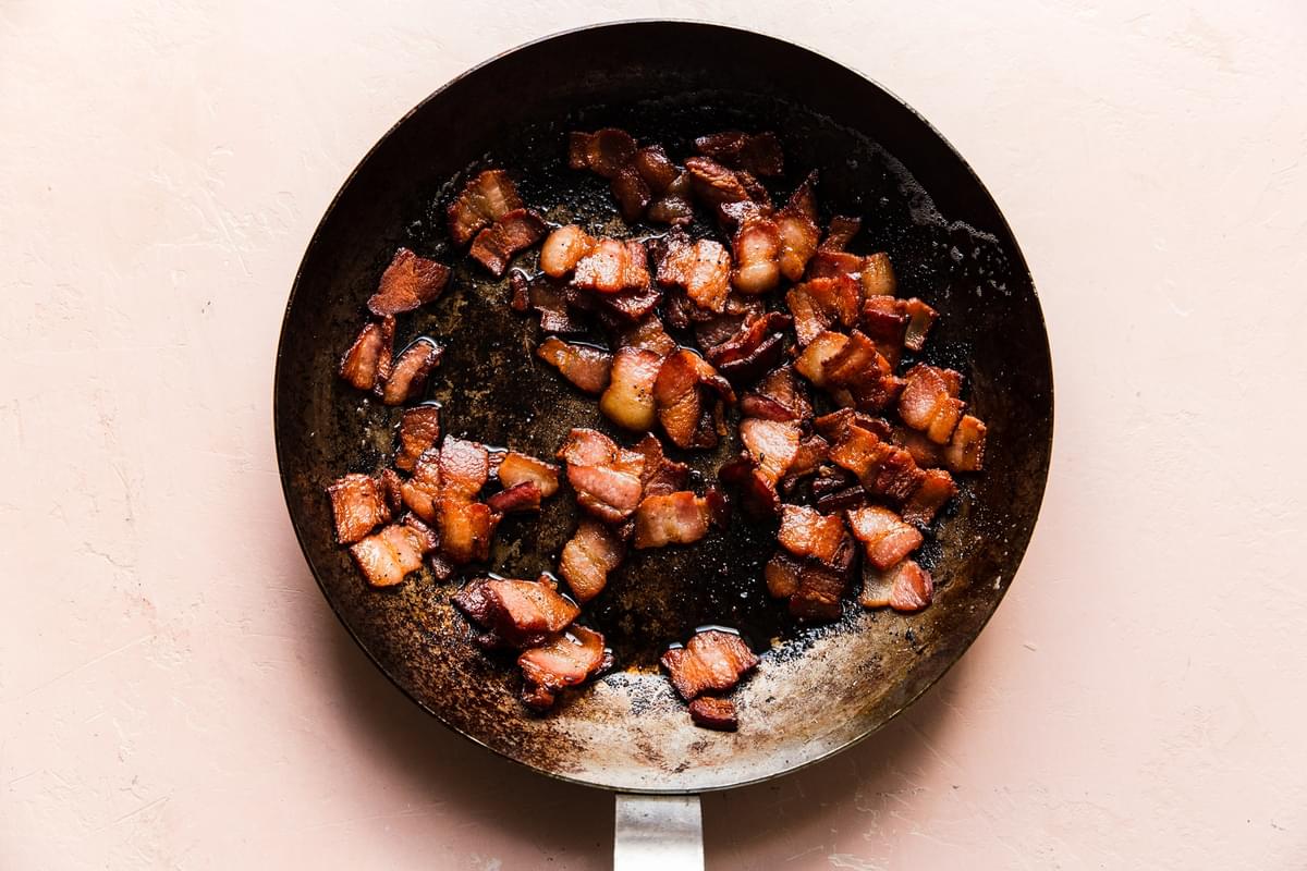 bacon pieces being cooked in a skillet