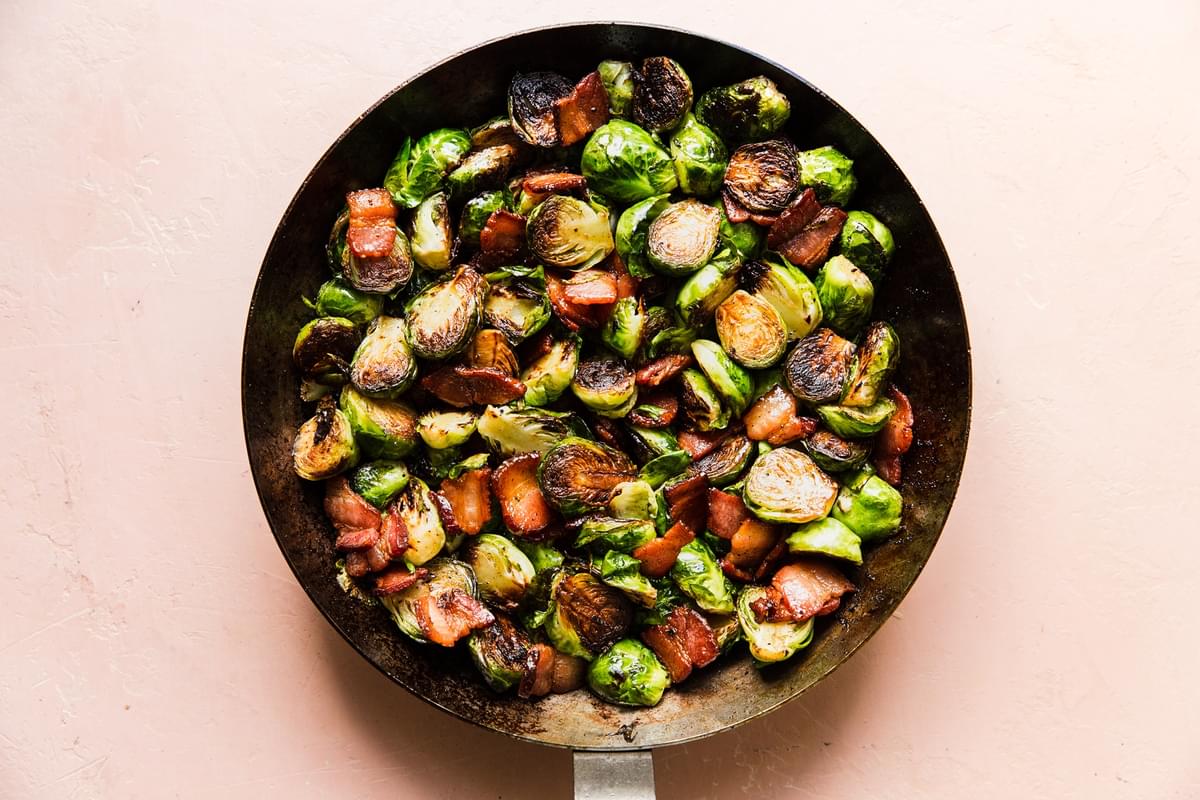 maple bacon brussels sprouts in a skillet seasoned with salt and pepper