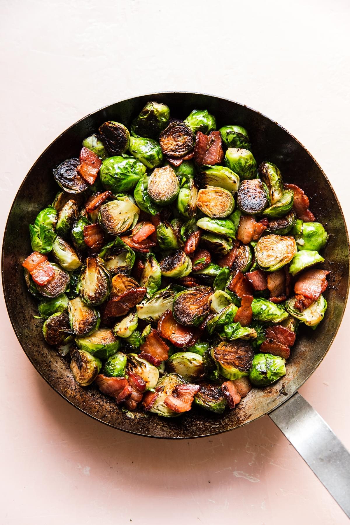 a skillet of homemade maple bacon brussels sprouts seasoned with salt and pepper