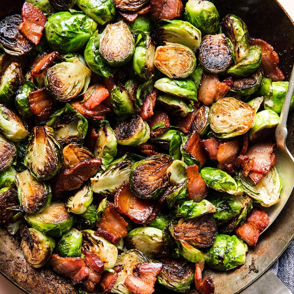 skillet of crispy maple bacon brussels sprouts seasoned with salt and pepper