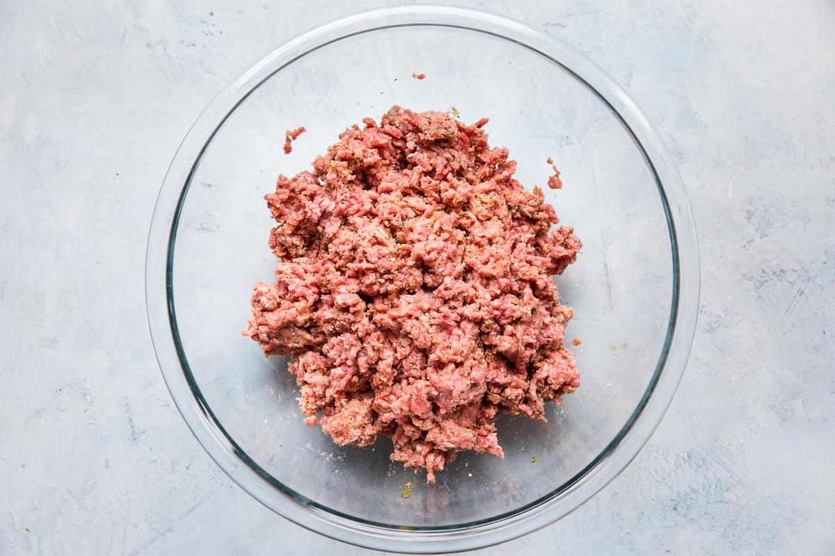 ground beef, seasonings, egg, bread crumbs, Worcestershire sauce and whole milk mixed together in a glass bowl for meatballs