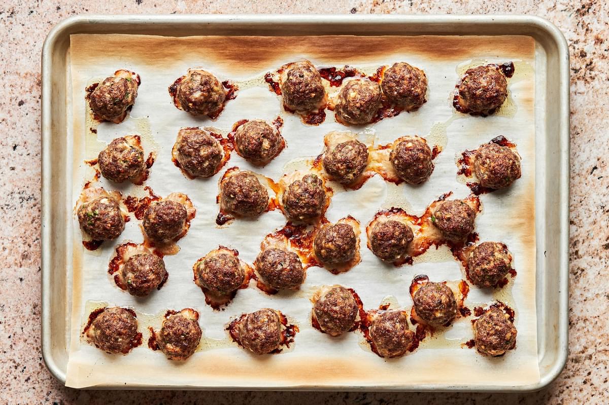 cooked meatballs on a baking sheet made with beef, egg, Worcestershire, breadcrumbs, parsley, parmesan, garlic & spices