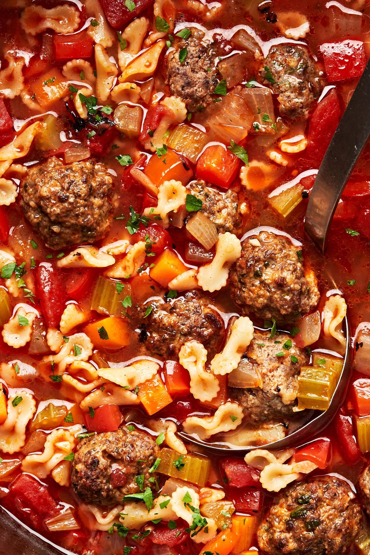 a close up picture of meatball soup made with beef meatballs, vegetables, spices, tomato paste and small pasta