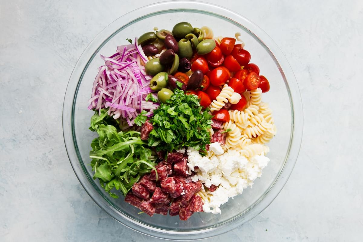 Mediterranean Pasta Salad in a bowl with feta, olives, tomatoes and arugula in a bowl