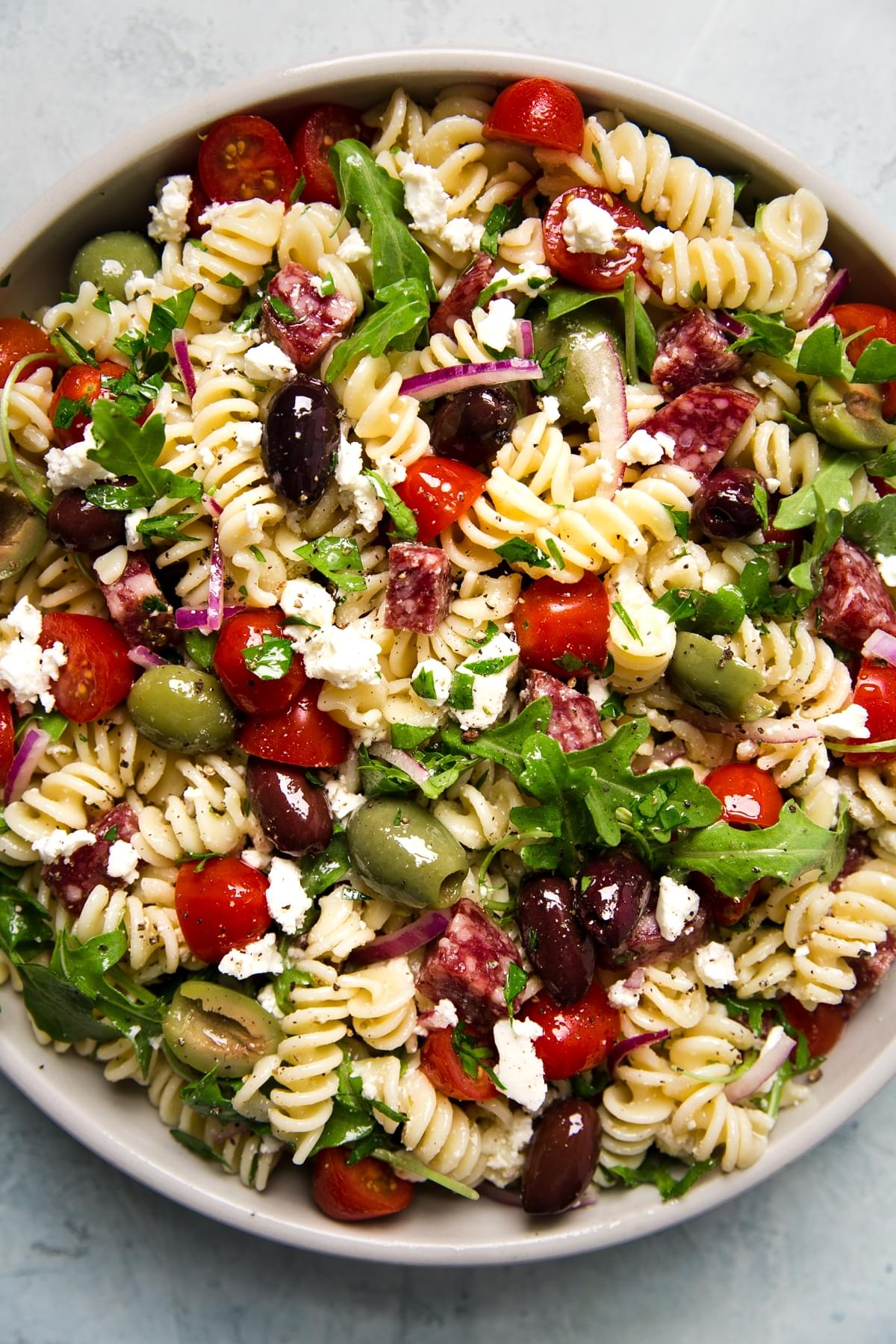 Mediterranean Pasta Salad in a bowl with feta, olives, tomatoes and arugula