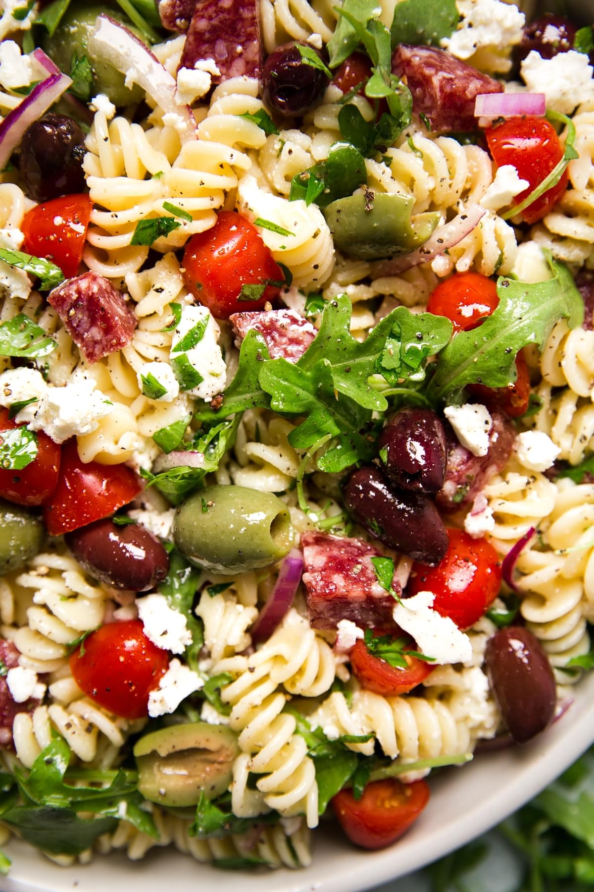 close up of Mediterranean Pasta Salad in a bowl with feta, olives, tomatoes and arugula