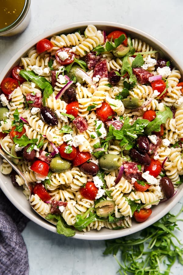 Mediterranean Pasta Salad in a bowl with feta, olives, tomatoes and arugula