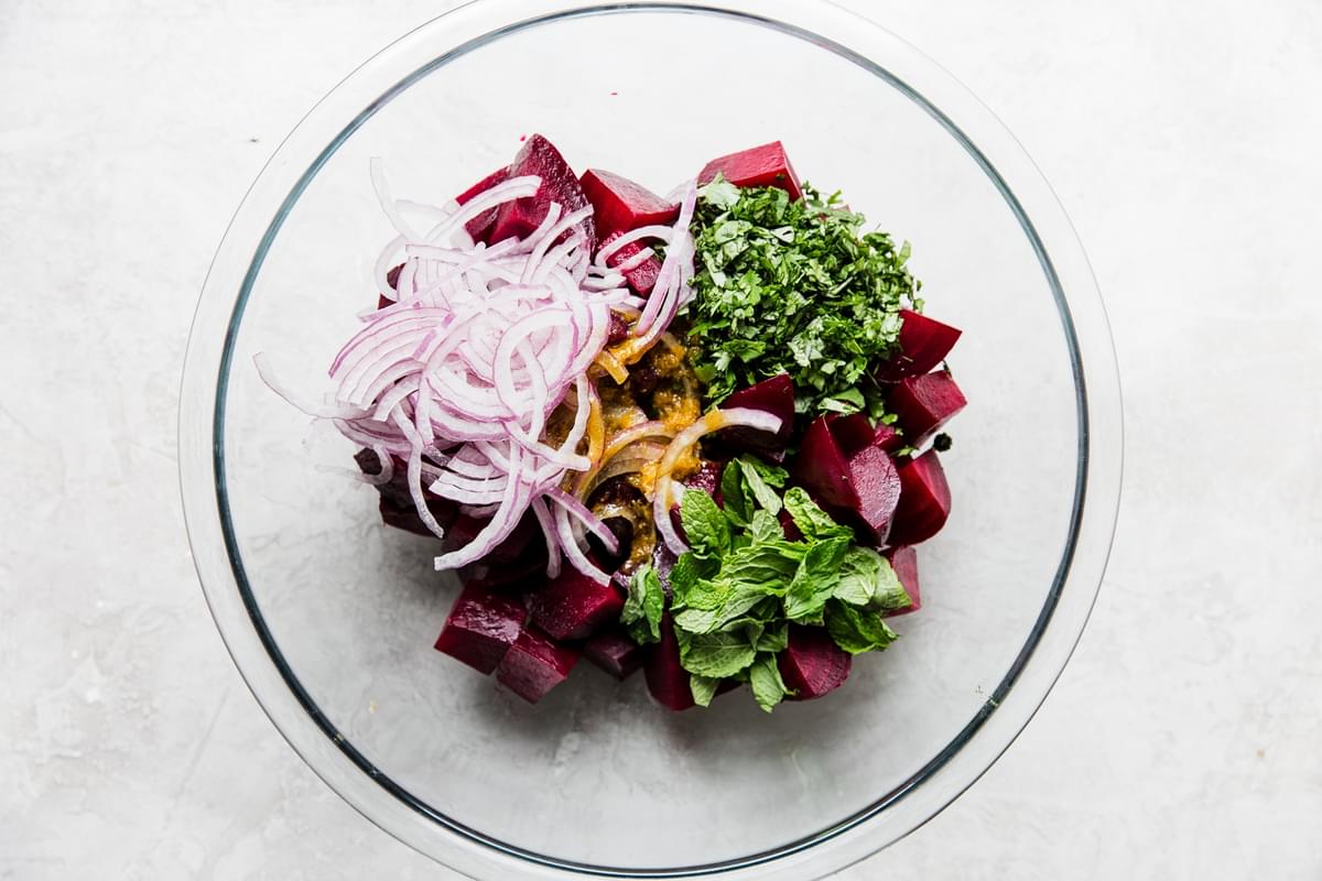 red onions, red beets, mint, cilantro and Moroccan salad dressing in a large glass bowl