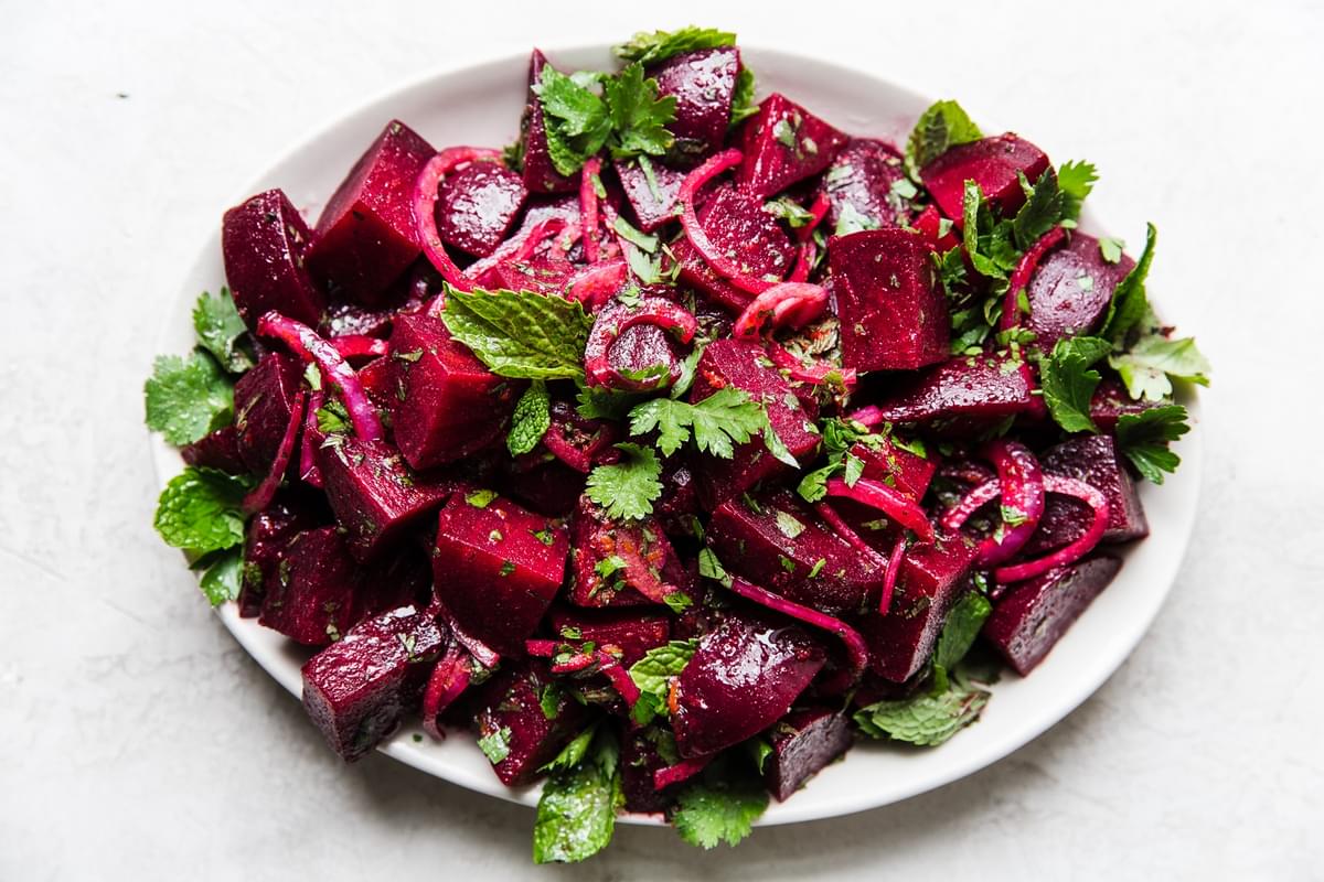 moroccan beet salad on a white platter with fresh mint and cilantro