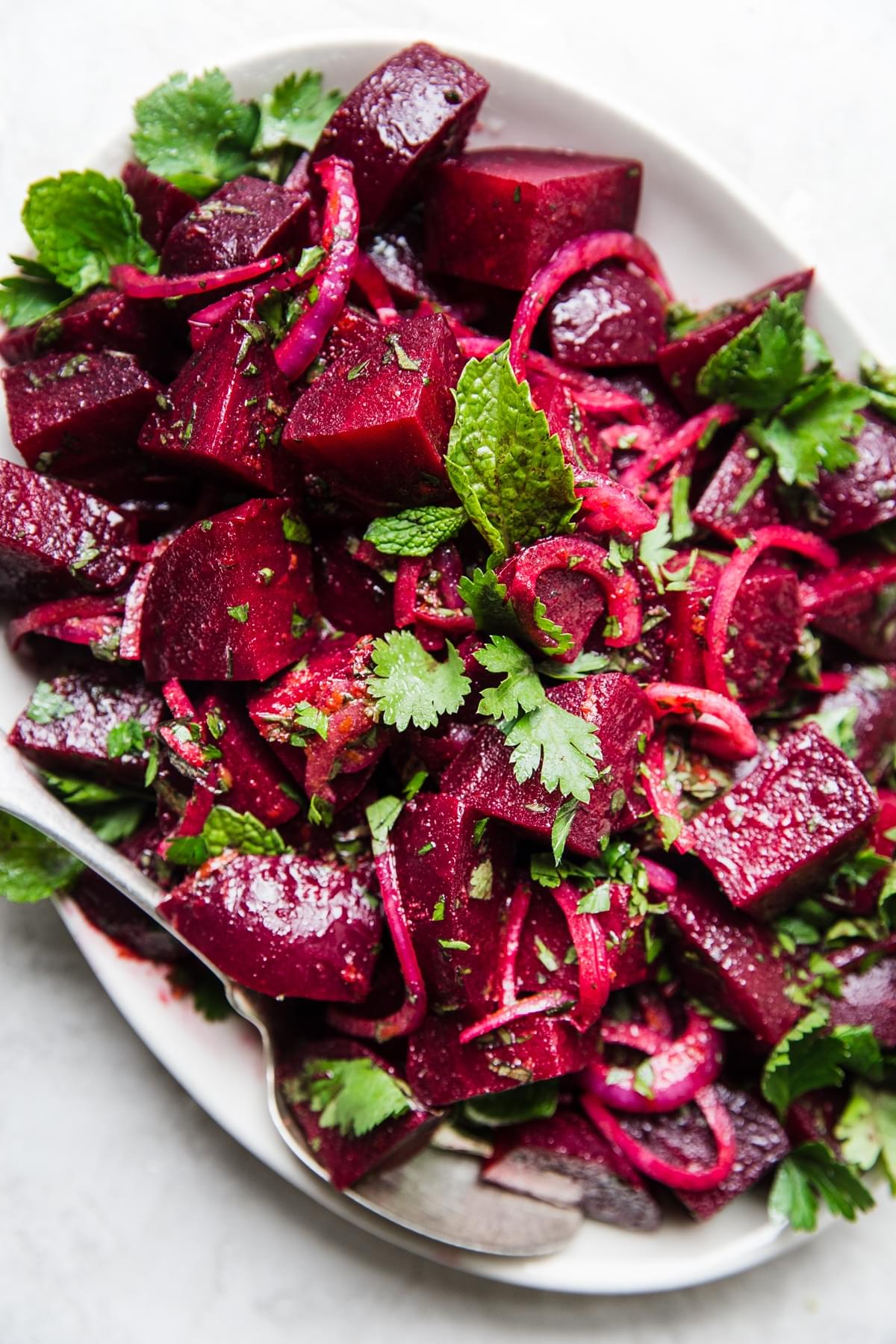 Moroccan beet salad on a white platter with fresh cilantro and fresh mint
