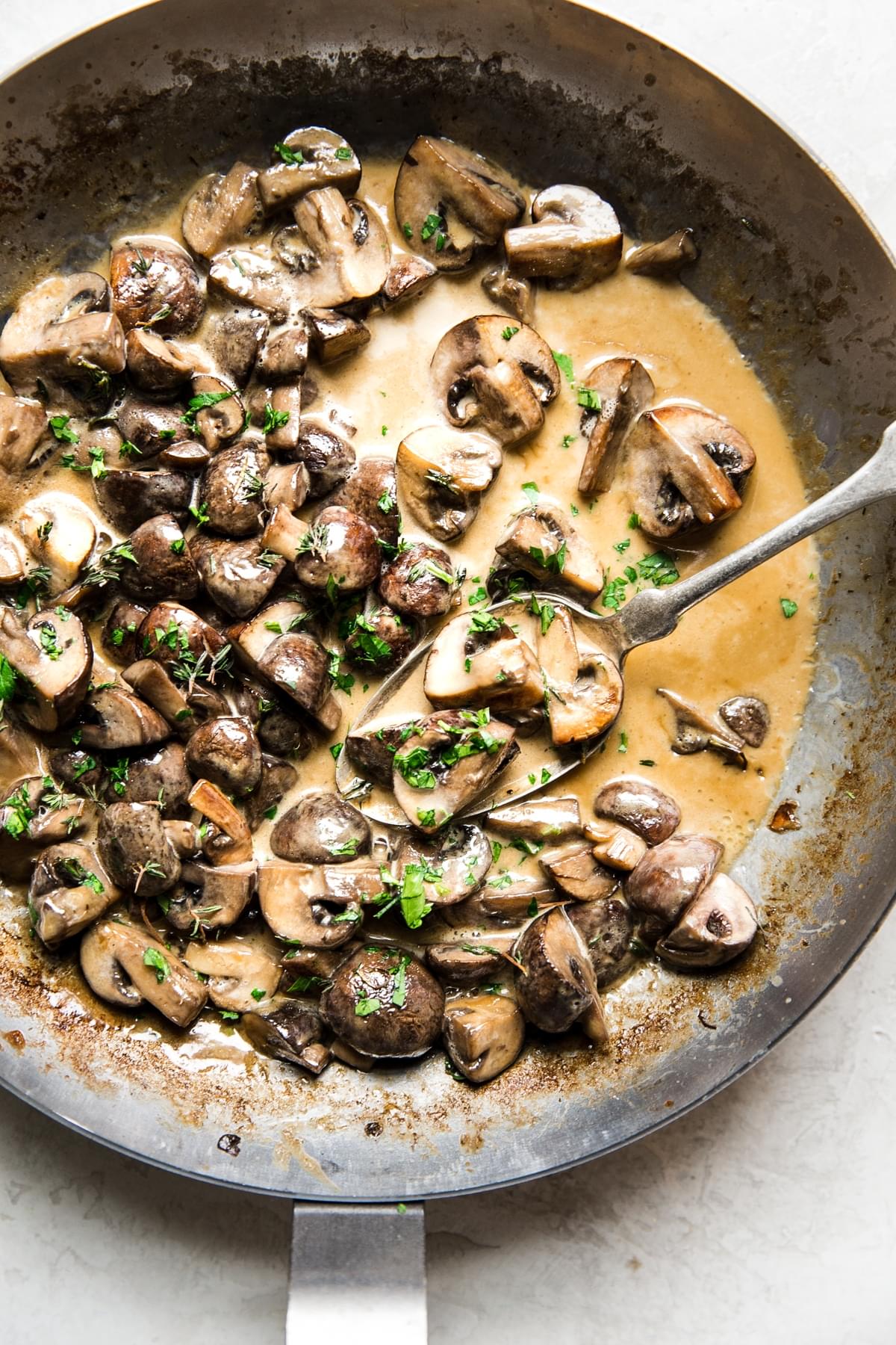 mushroom sauce made with heavy cream, soy sauce, thyme and butter in a skillet with a spoon