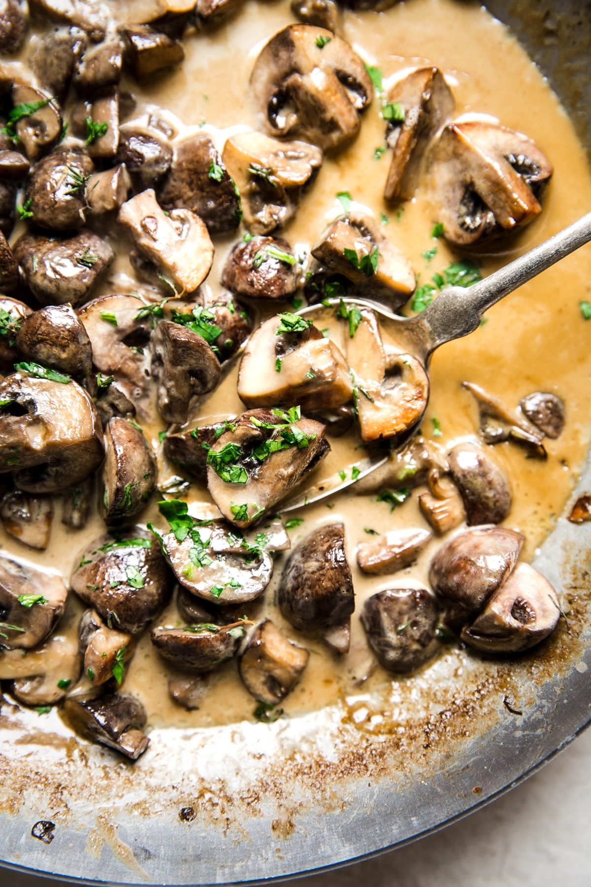 Creamy mushroom sauce made with thyme in a pan with a spoon