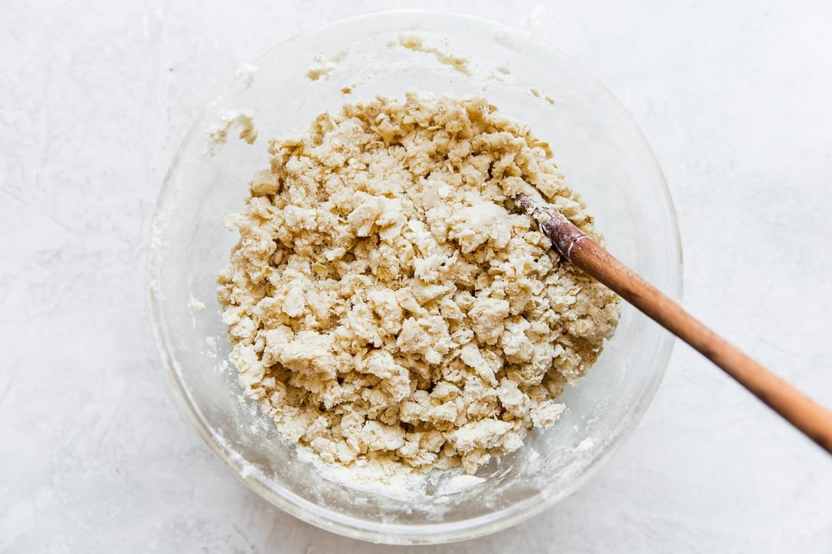 ingredients for oat scones in a glass bowl with a wooden spoon