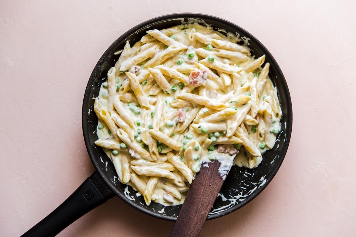 stirring Pasta With Peas Pancetta And Goat Cheese in a pan