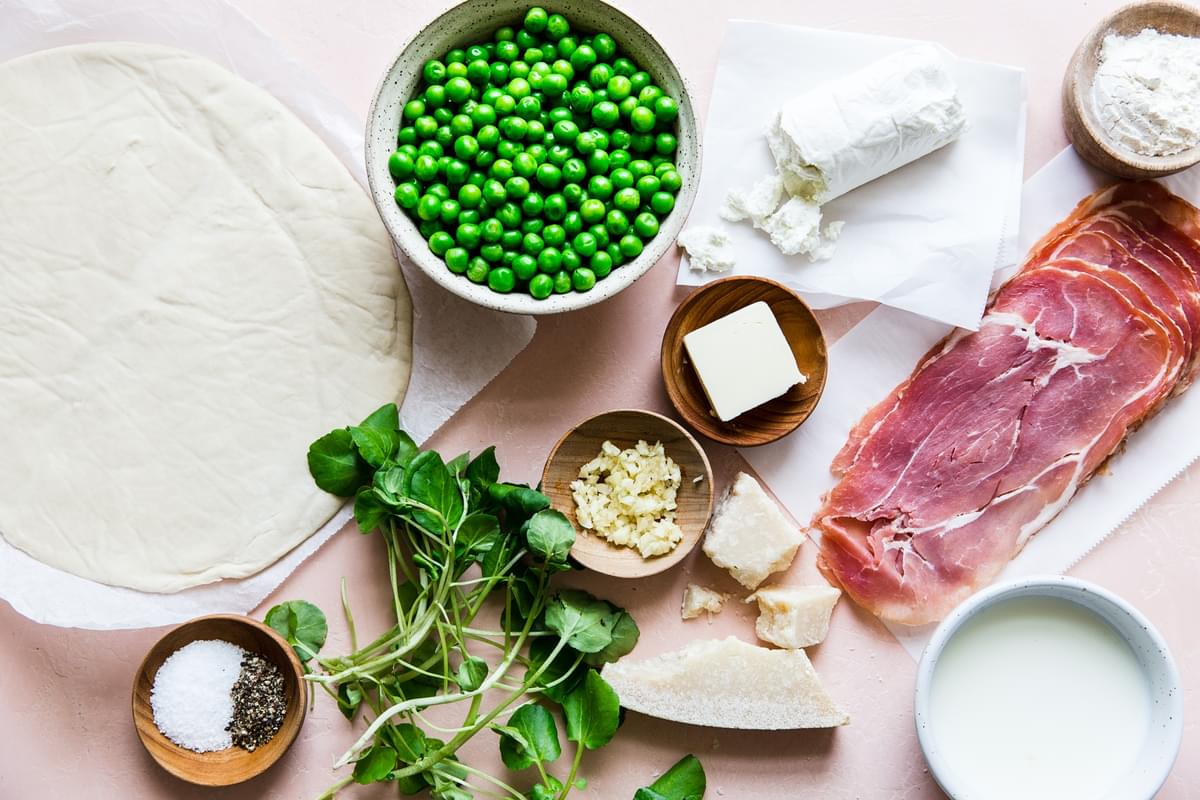 ingredients for spring pizza. dough, butter, garlic, Pea and prosciutto goat cheese parmesan cheese