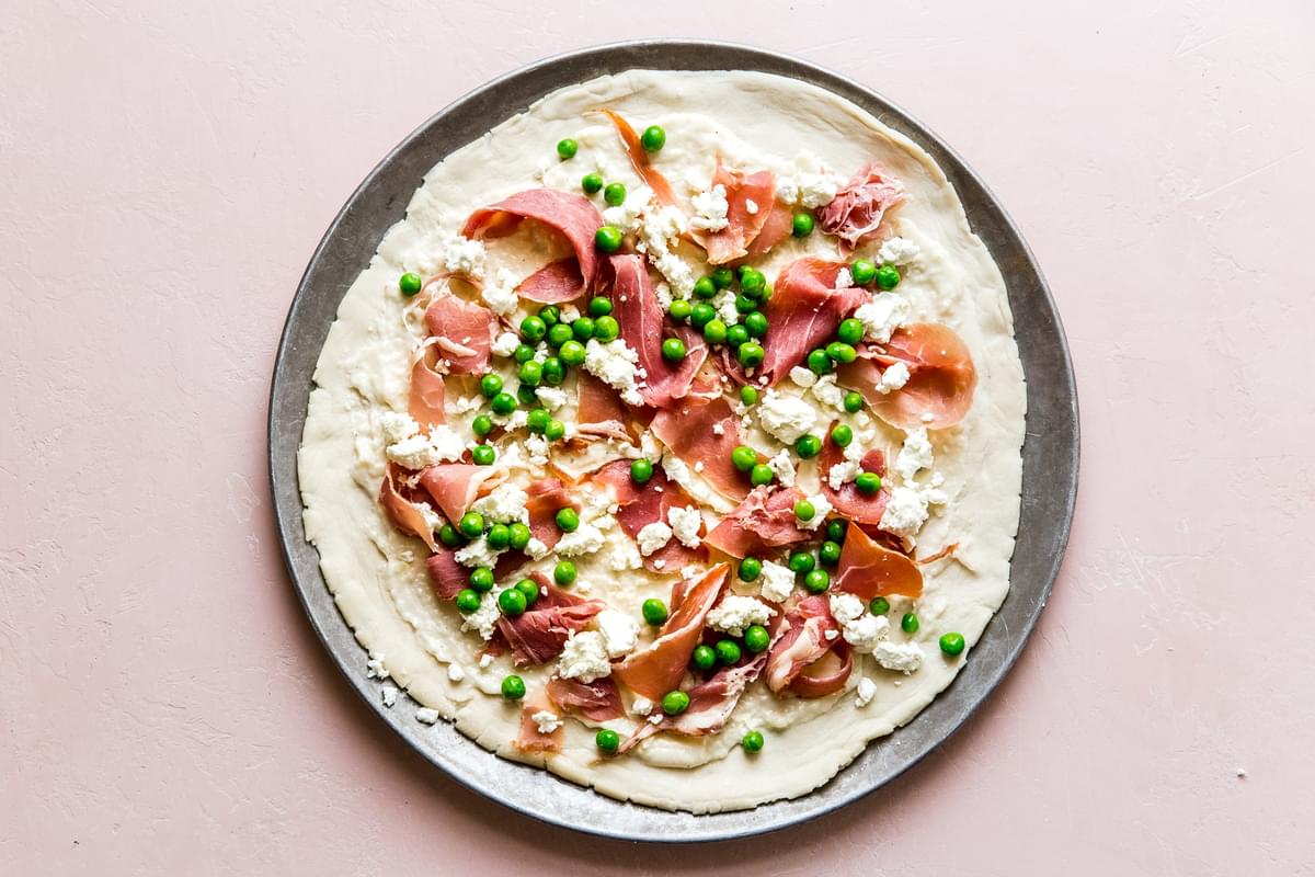Pea and prosciutto spring pizza with goat cheese cream sauce