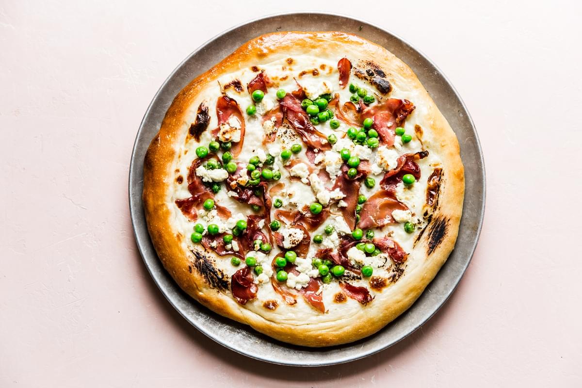 Pea and prosciutto pizza with goat cheese cream sauce and parmesan cheese