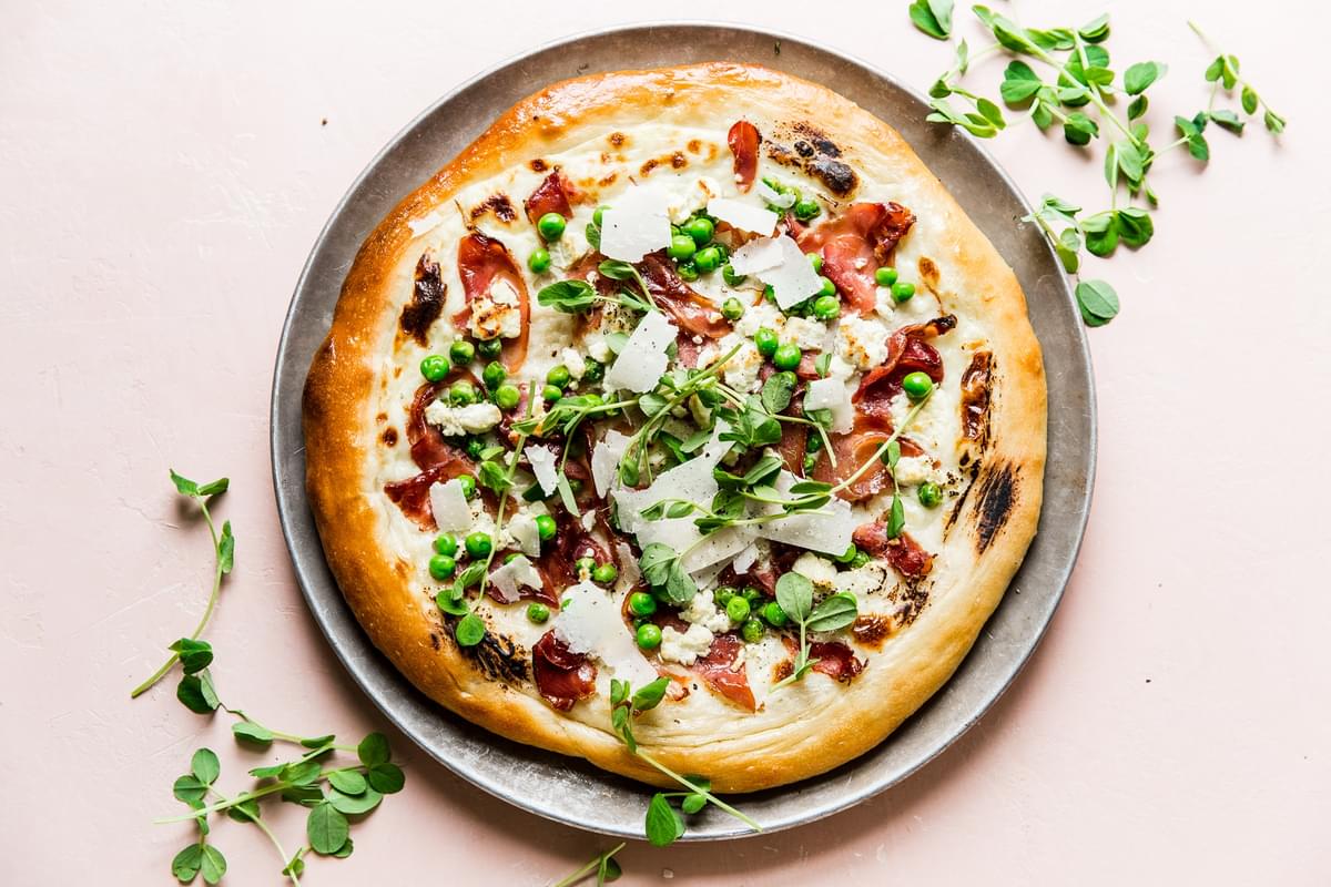 Pea and prosciutto pizza with goat cheese cream sauce parmesan cheese spring pizza
