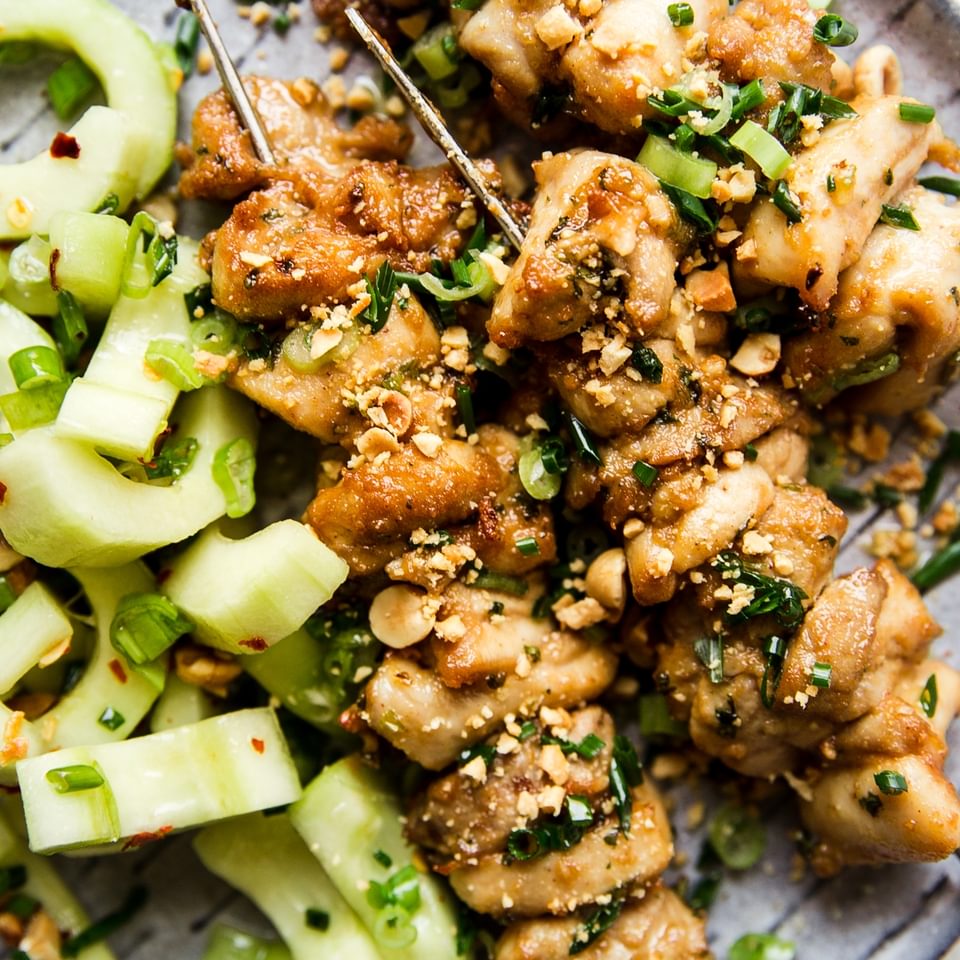 Peanut Sauce Marinated Chicken Skewers on a plate with cucumber salad