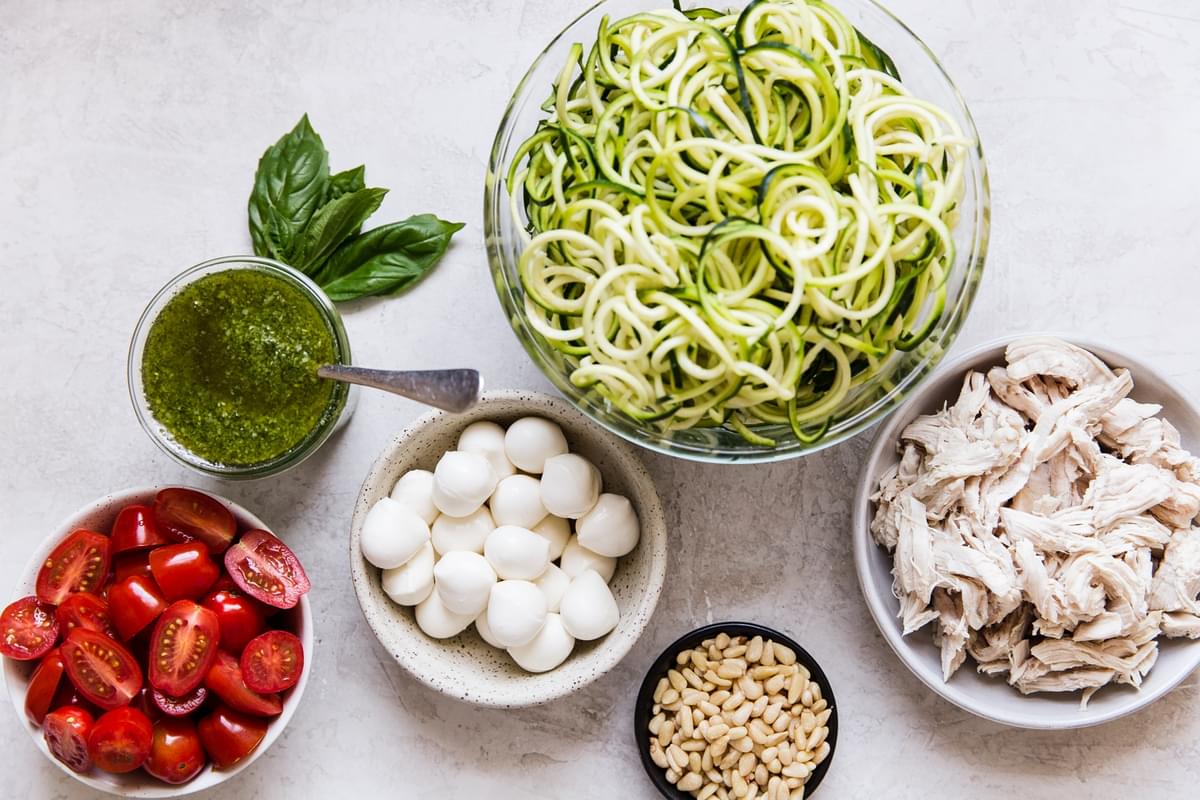 ingredients for pesto zoodle salad in small bowls