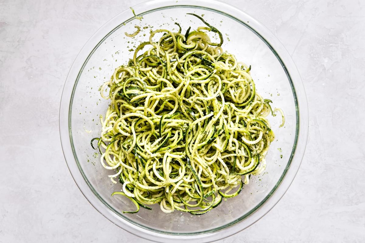 glass bowl of zoodles mixed with homemade basil pesto