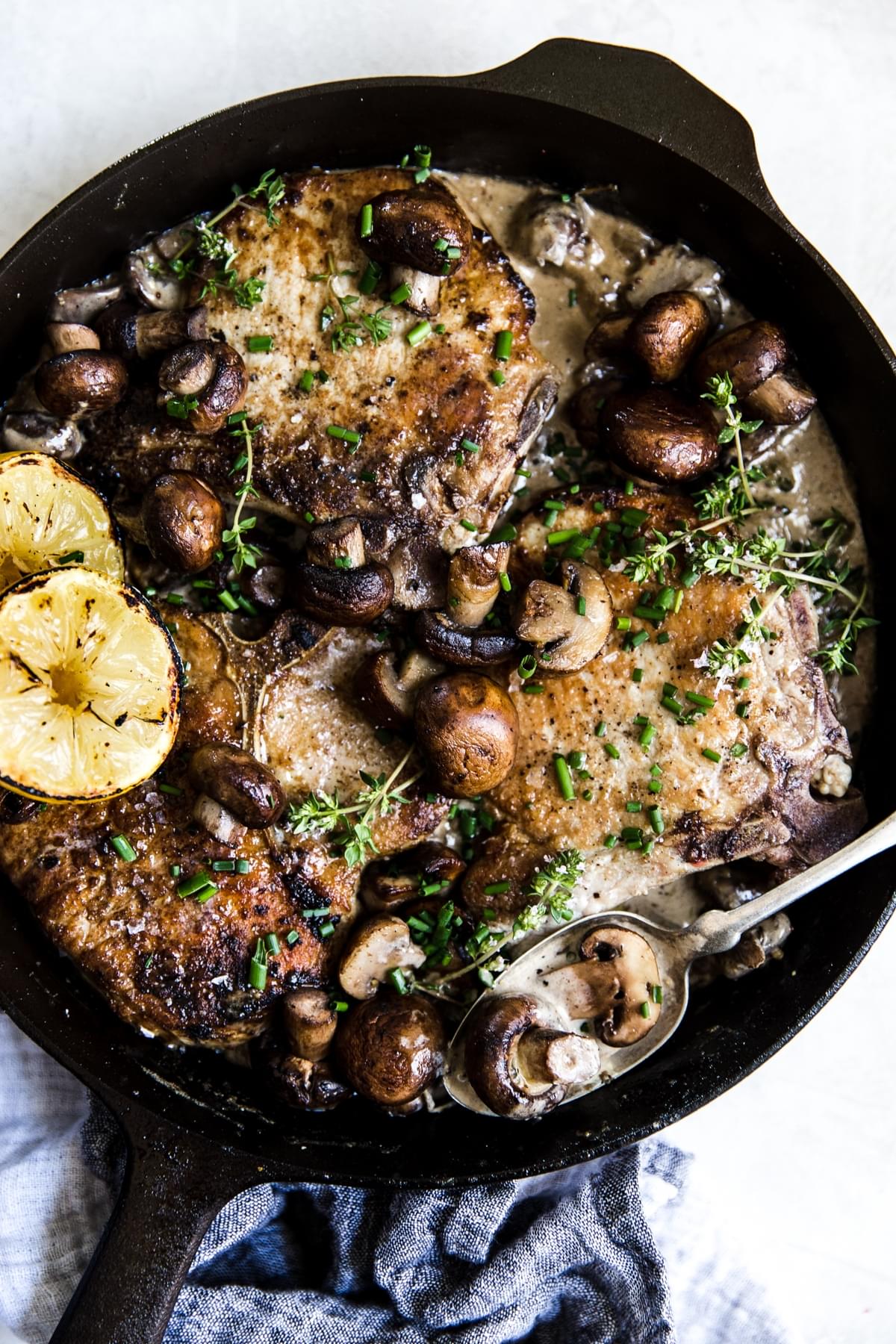 Pork Chops With Mushroom Cream Sauce in a cast iron skillet with a spoon