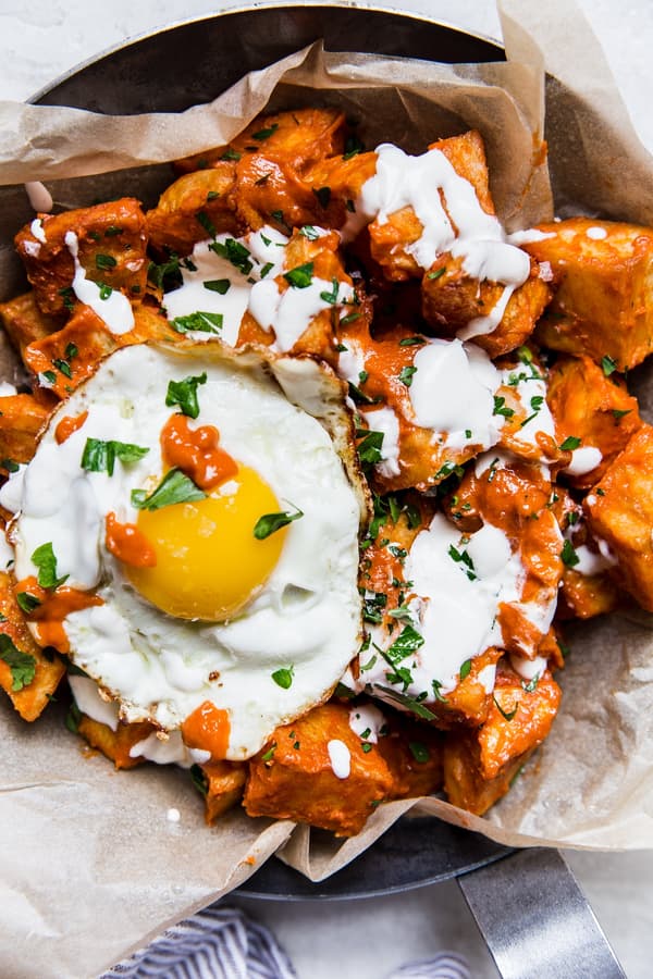 Potatoes bravas in a pan with a fried egg