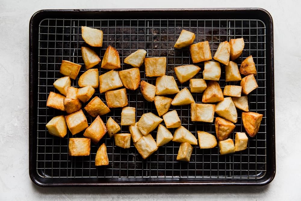 deep fried potatoes on a cooling rack on a baking sheet
