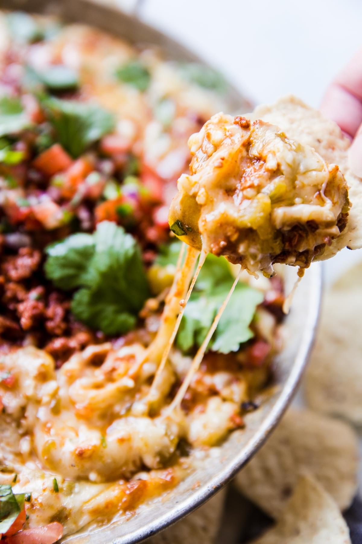 Cheese pull of Queso Fundido Dip with tortilla chip