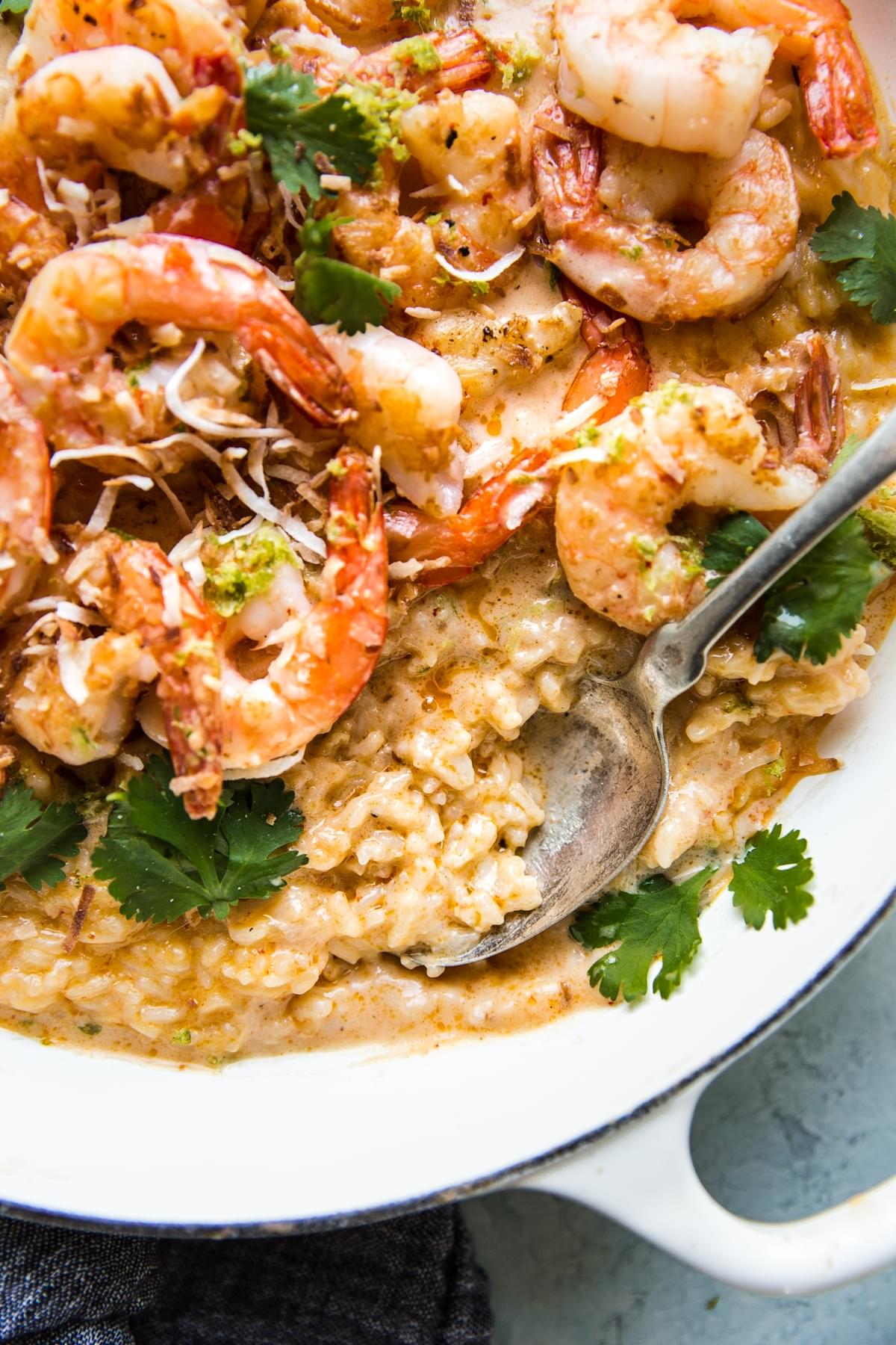 spoon dipped in red curry risotto topped with shrimp