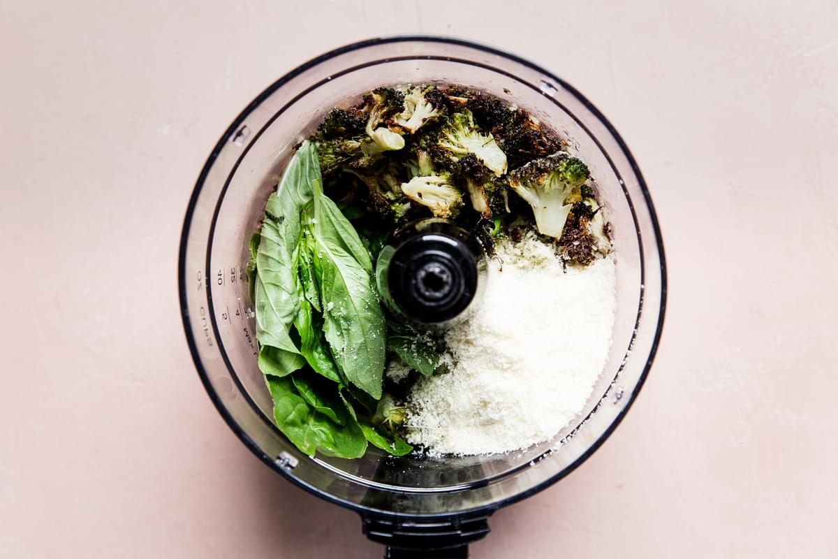 food processor with roasted broccoli, fresh basil, parmesan cheese and garlic