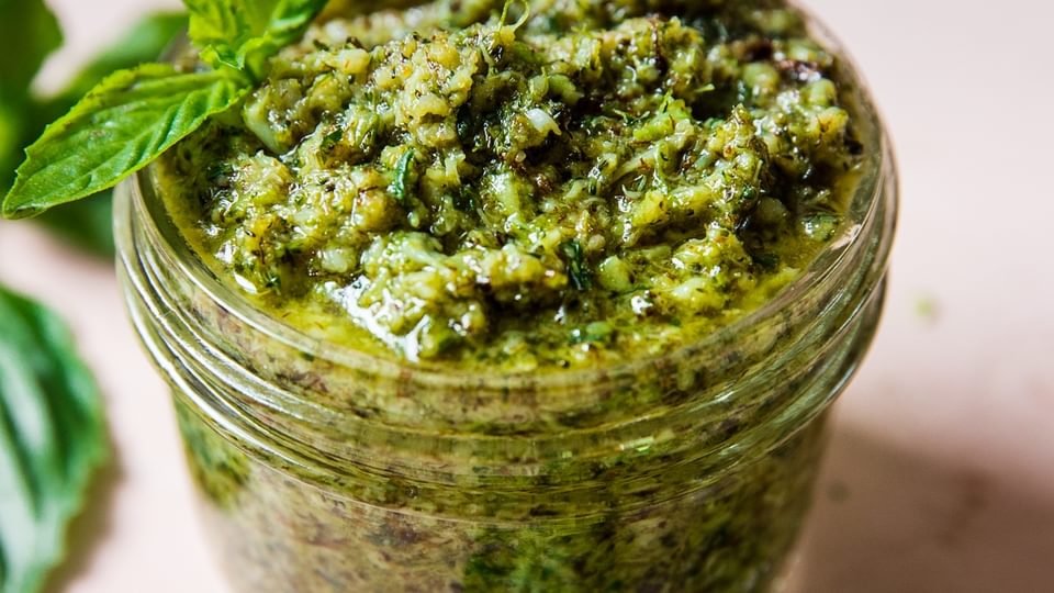 roasted broccoli pesto in a jar topped with fresh basil
