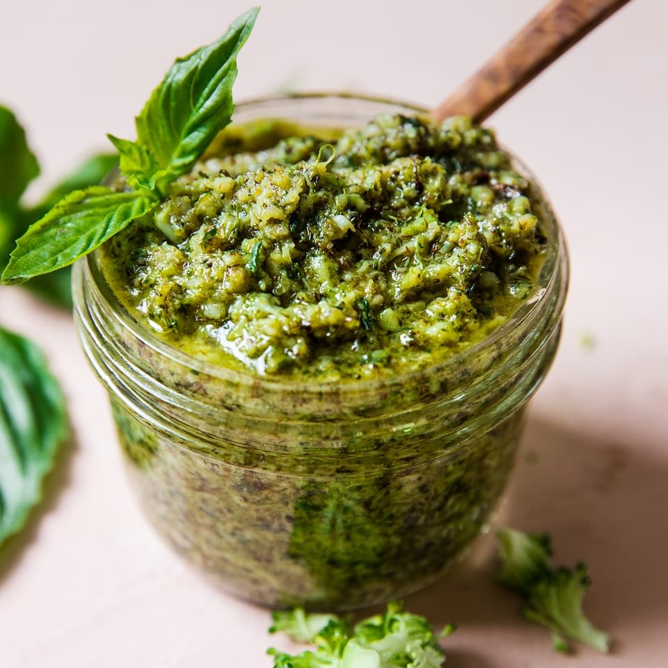 roasted broccoli pesto in a jar topped with fresh basil