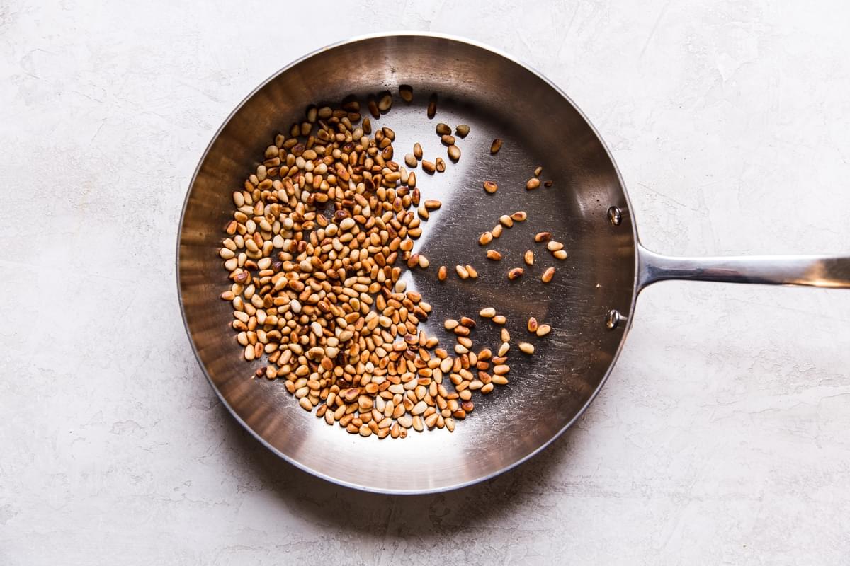Toasted pine nuts in a stainless steel skillet