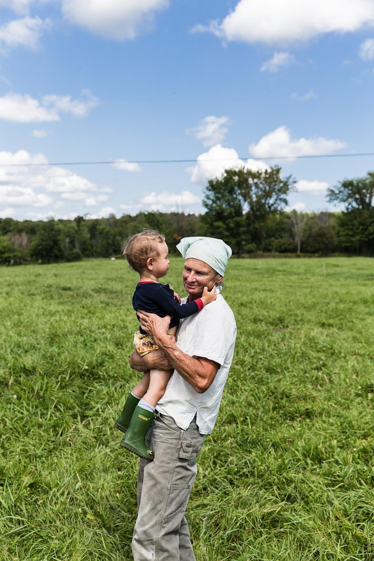 female farmer holding little boy on a grass field