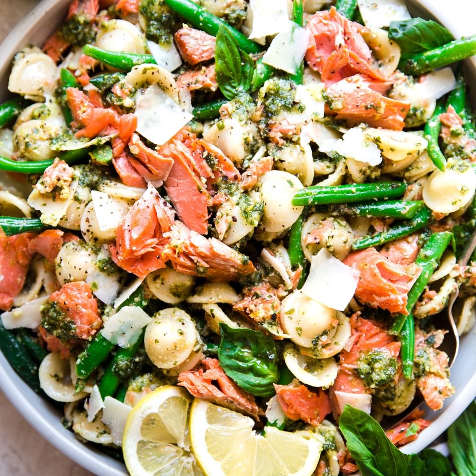 Salmon Pasta With Homemade Pesto in a bowl with green beans, orecchiette, basil, lemons and parmesan cheese.