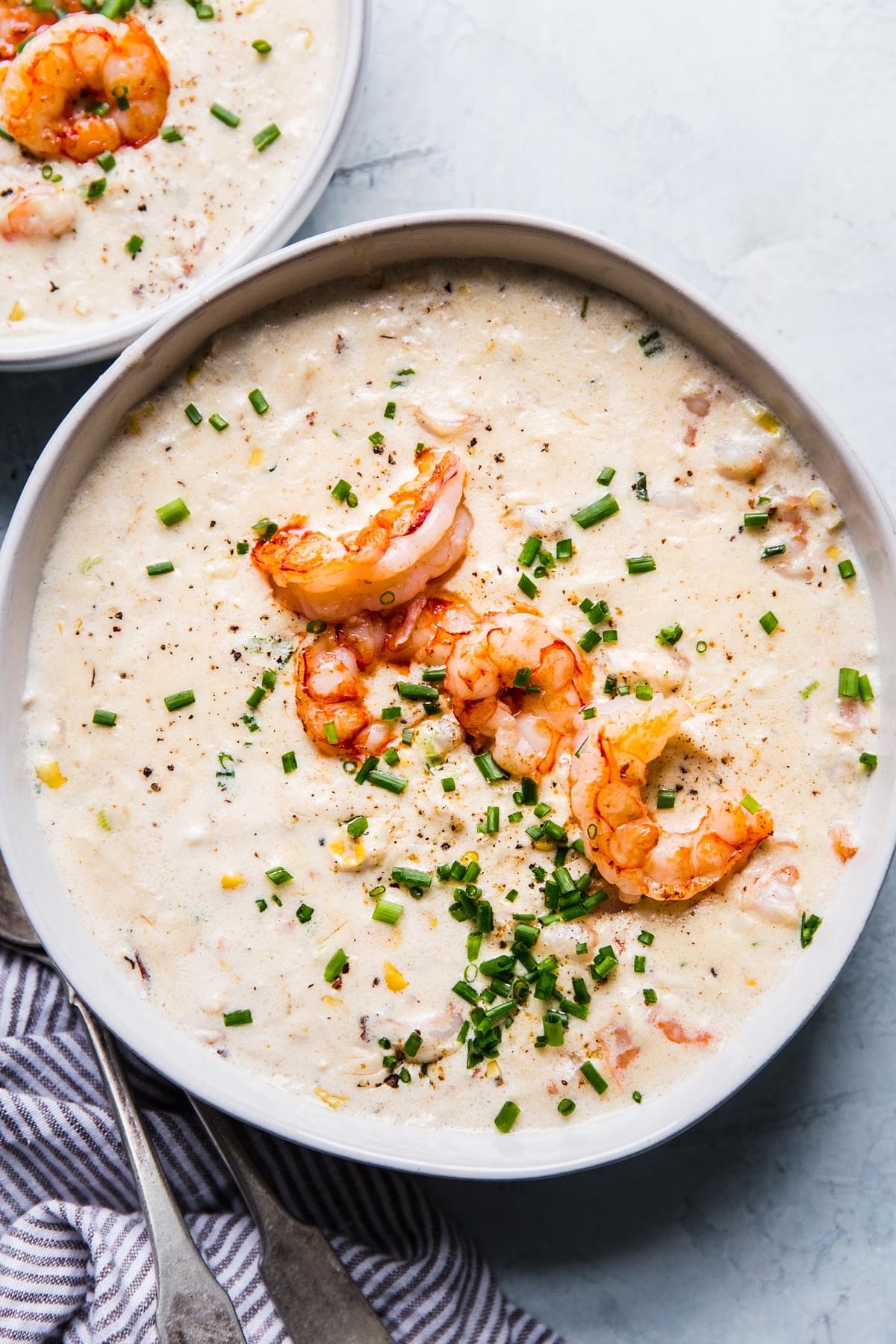 seafood bisque in a white bowl with shrimp and chives