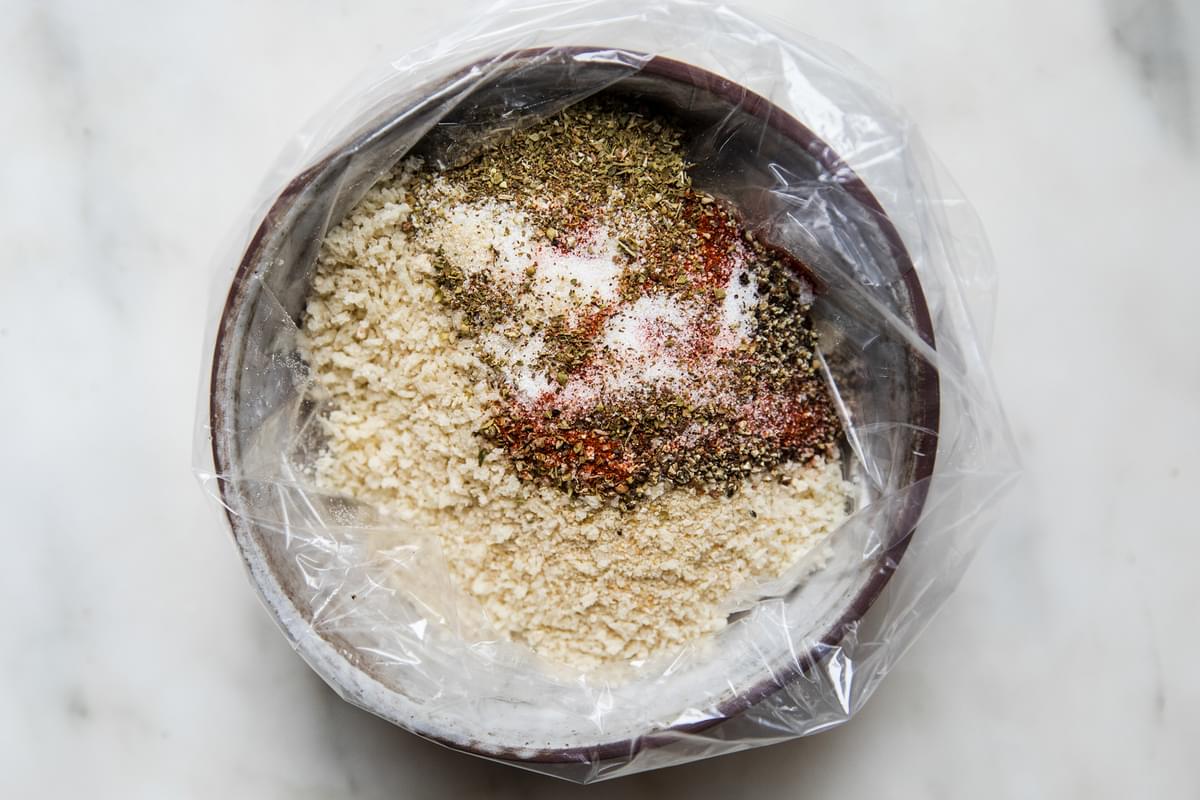 a bowl lined with a plastic bag filled with breadcrumbs and spices to coat chicken for homemade shake and bake chicken