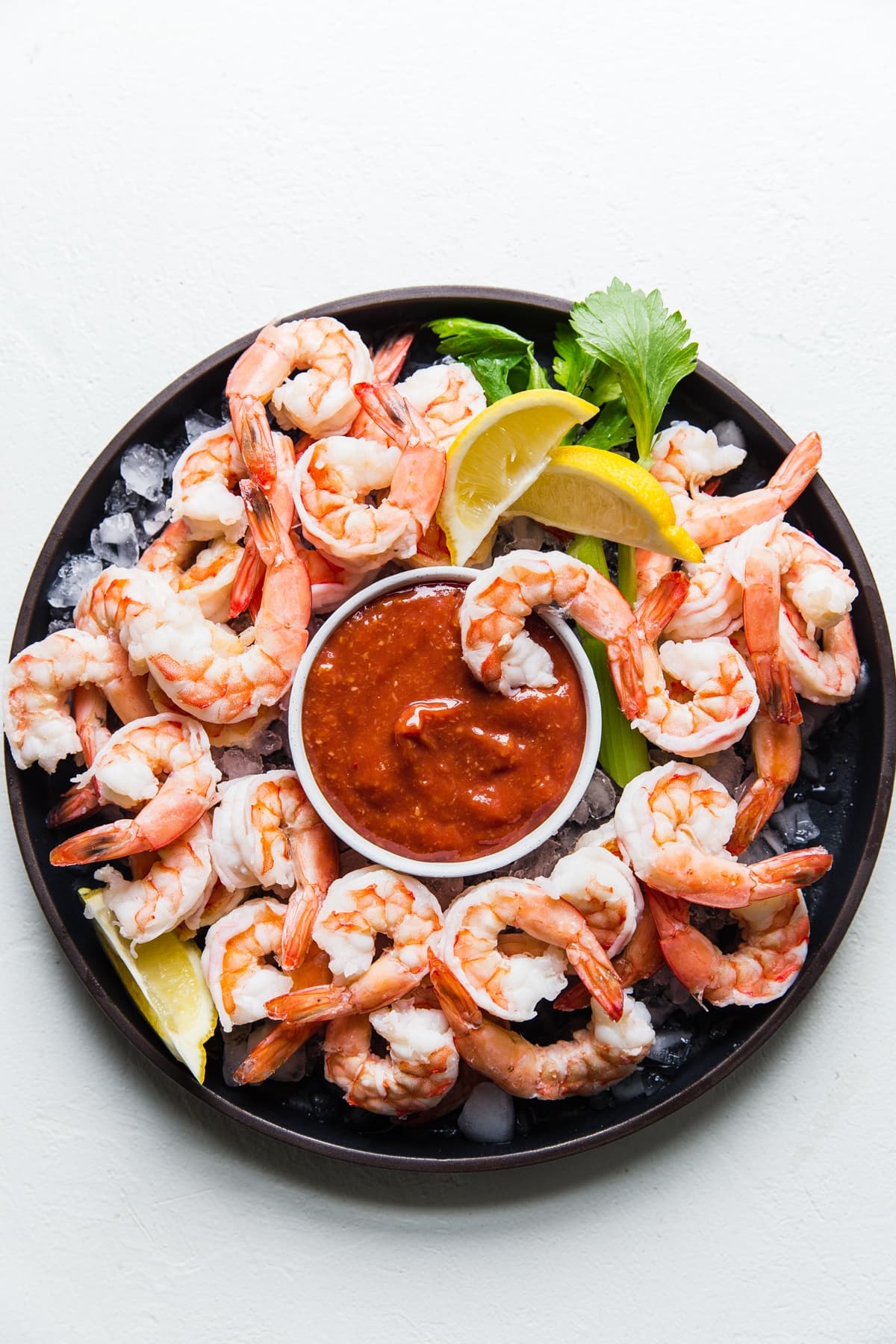 shrimp cocktail sauce with shrimp over ice on a black plate