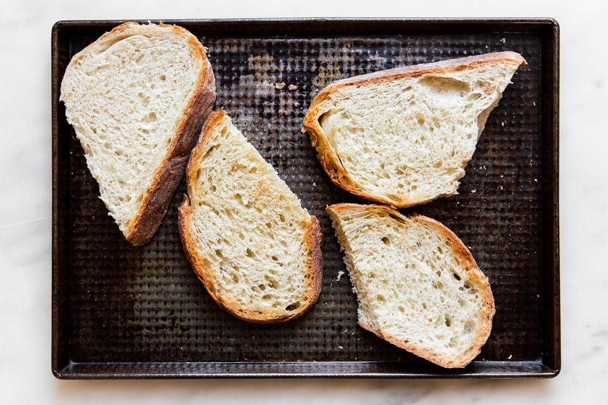 thick slices of rustic bread on a baking sheet